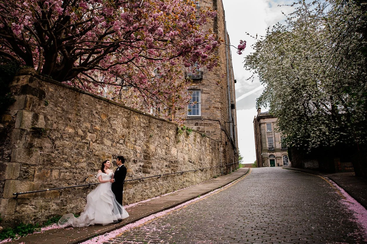 Bride and groom hugging under cherry blossom in Edinburgh