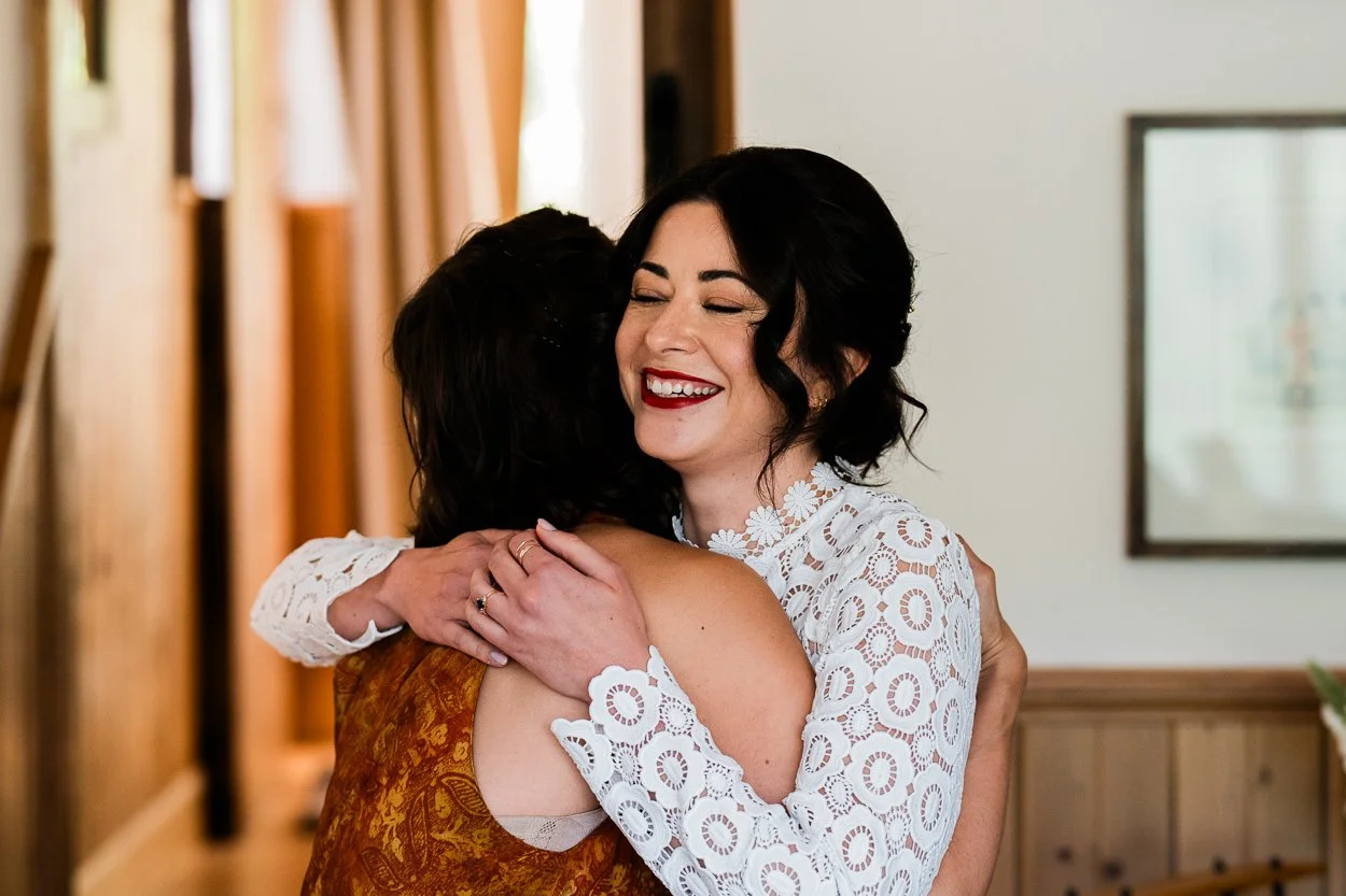 Bride hugging bridesmaid whilst smiling