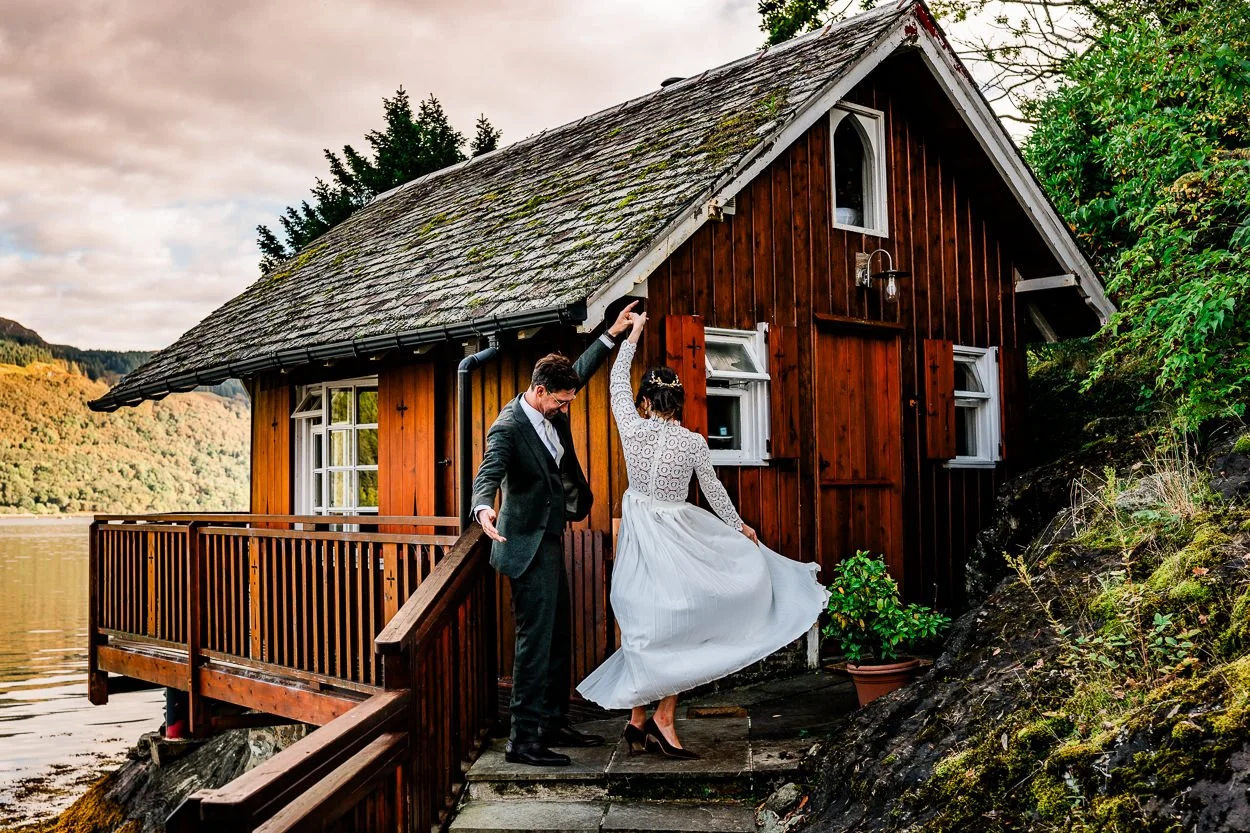 Bride-and-groom-dancing-in-front-of-lochside-cabin-scotland