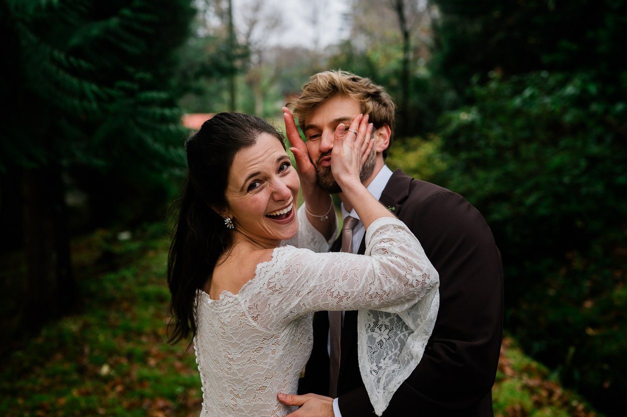 Bride-and-groom-playfully-grabbing-each-others-faces-during-wedding