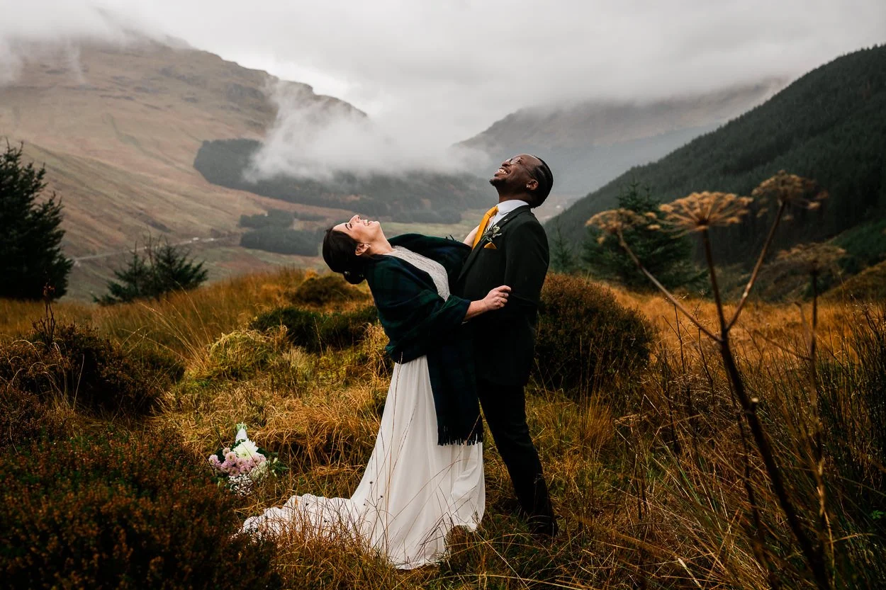 Bride-and-groom-laughing-on-top-of-a-mountain-scottish-elopement