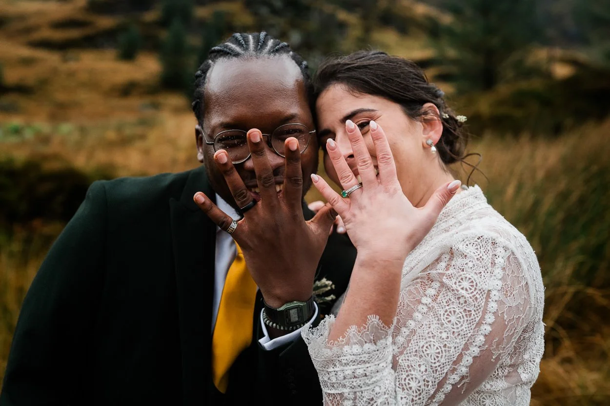 Bride and groom holding their hand up to camera to show rings