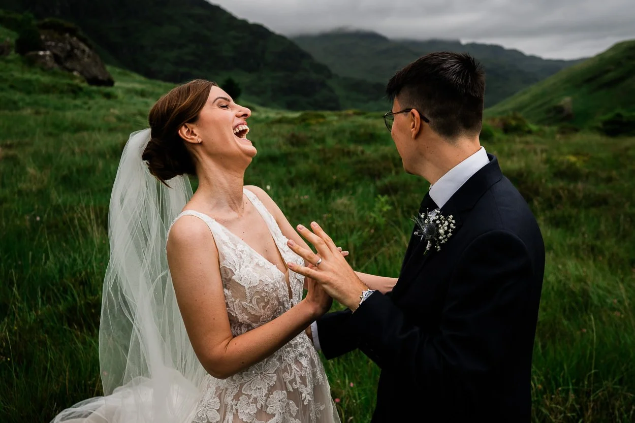 Bride and groom embracing and laughing on top of Scottish mountain