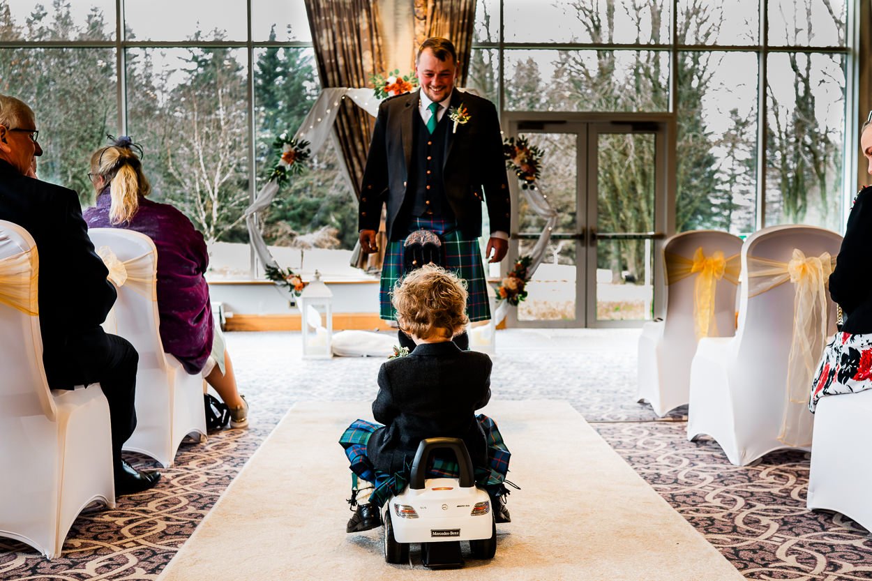 Grooms-son-driving-down-aisle-in-a-toy-car