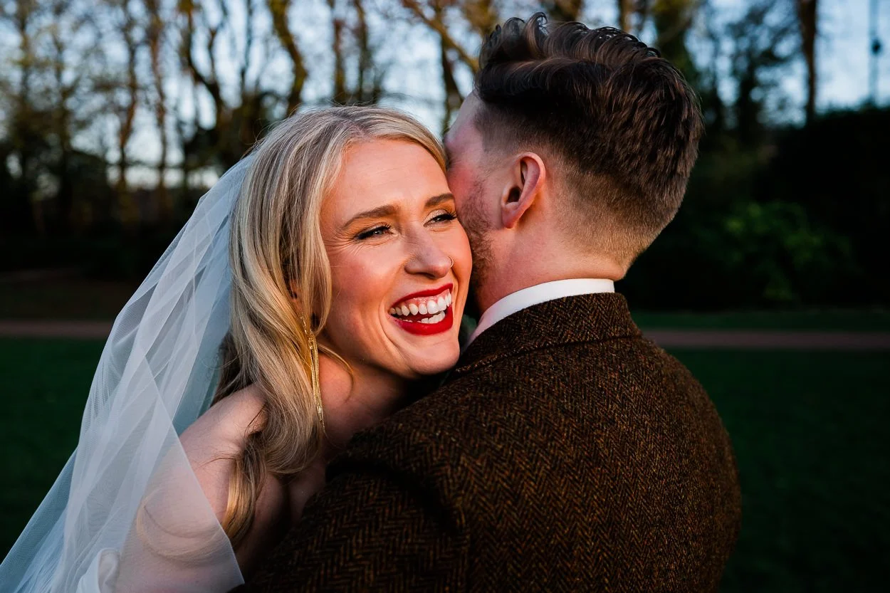 Bride with red lips smiling and hugging groom