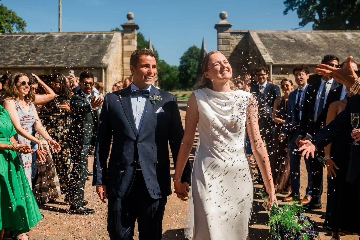 Bride and groom walking through confetti at Rosebery Steading