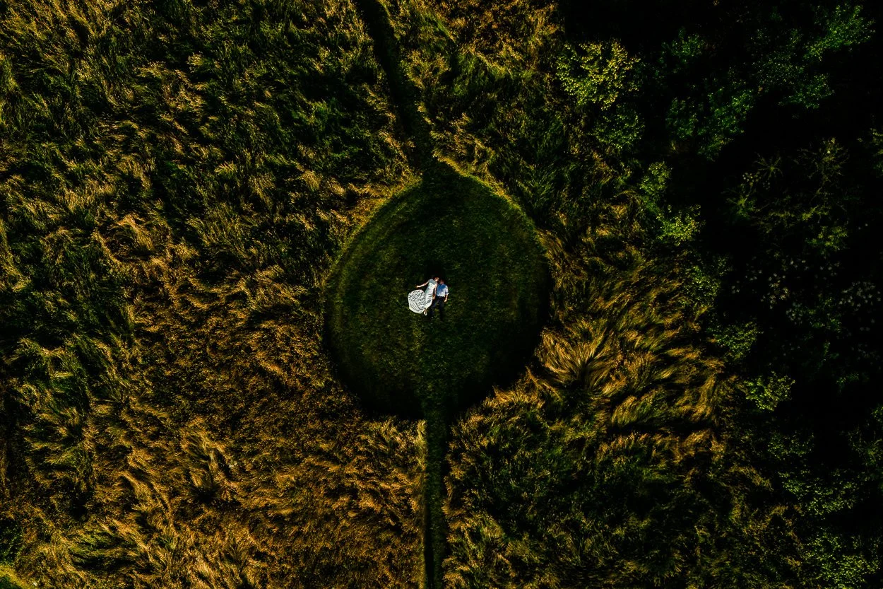 Birds Eye view drone photograph of bride and groom lying down in a field