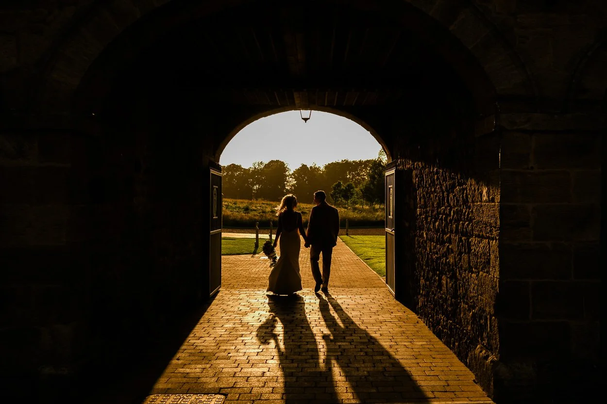 Bride and groom silhouette through archway at Rosebery Steading 