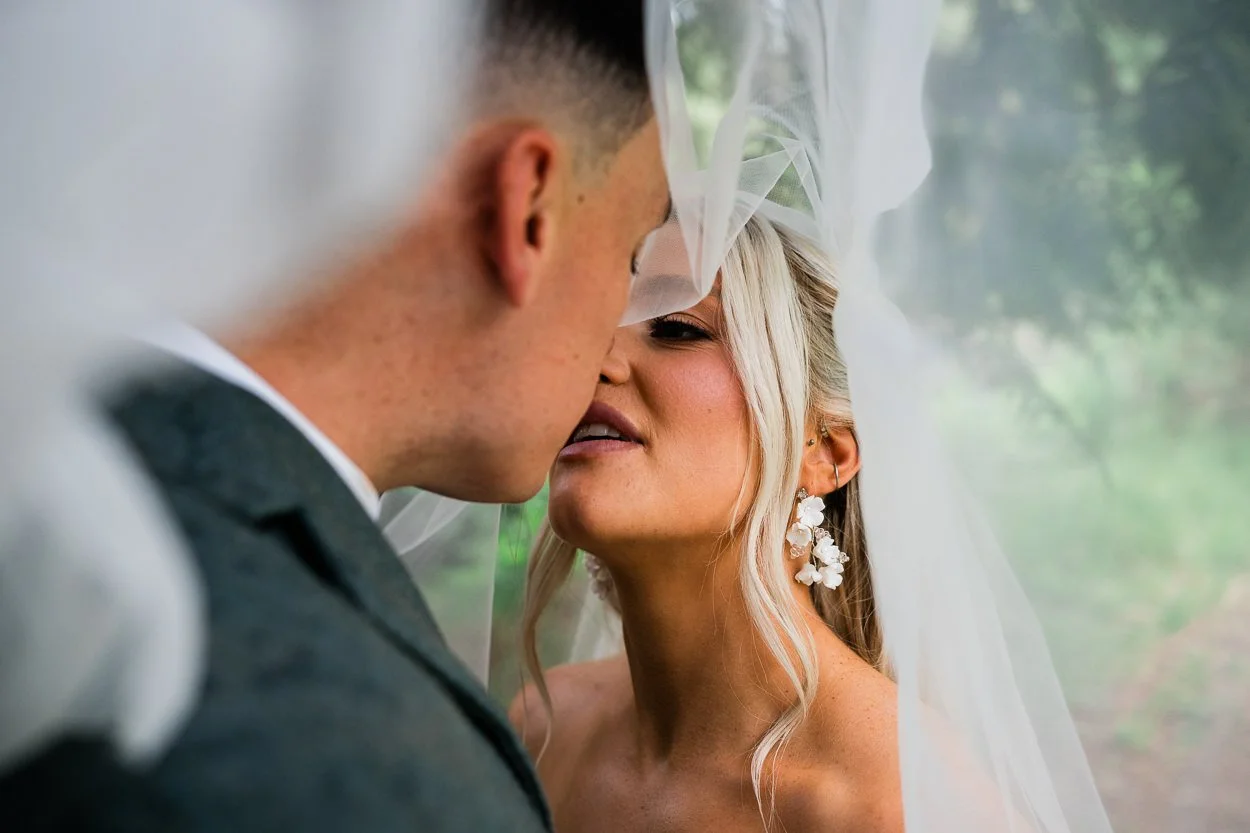 Bride and groom kissing romantically under the wedding dress veil
