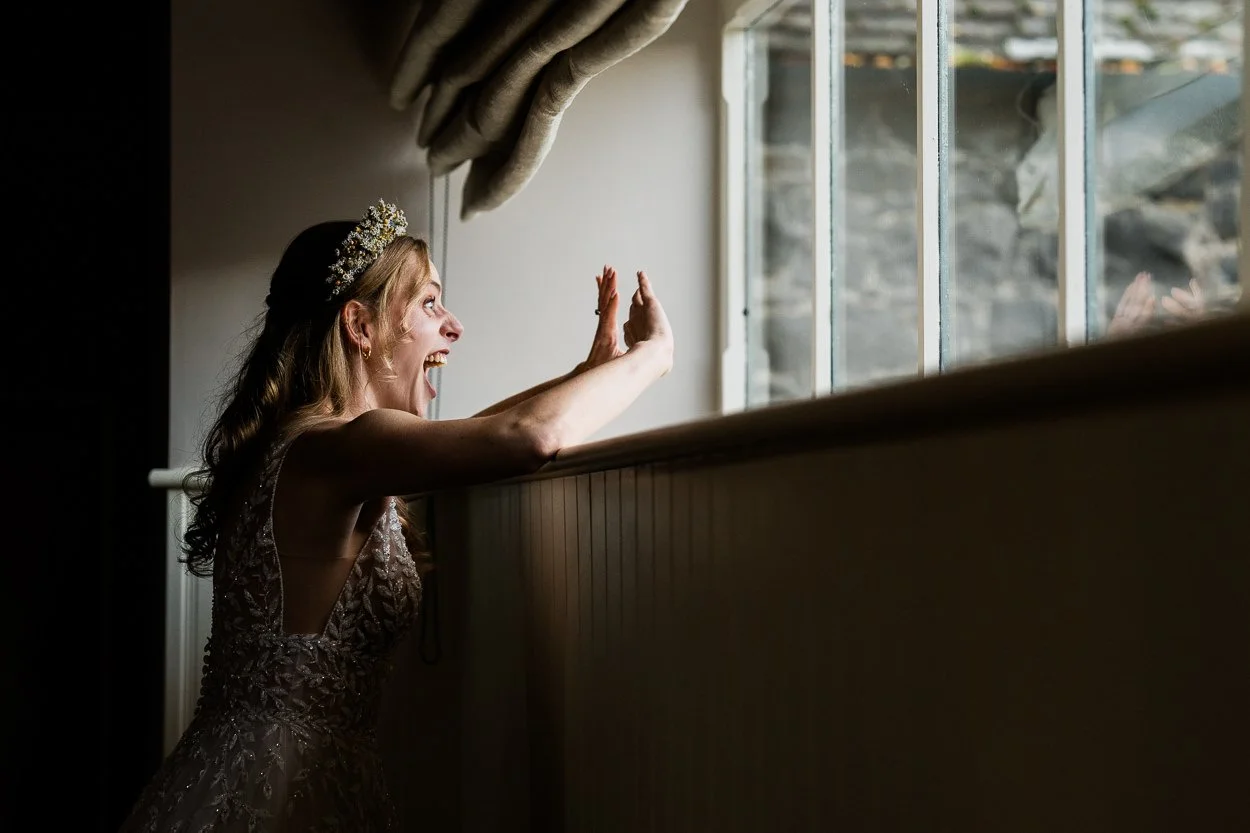 Bride seeing guests through window at Byre at Inchyra