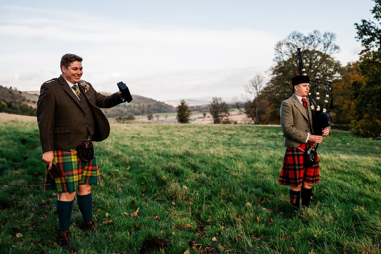 Groom and piper greeting guests for hilltop ceremony