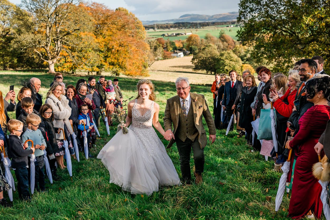 Bride and father walking up the aisle at hilltop ceremony at Byre at Inchyra