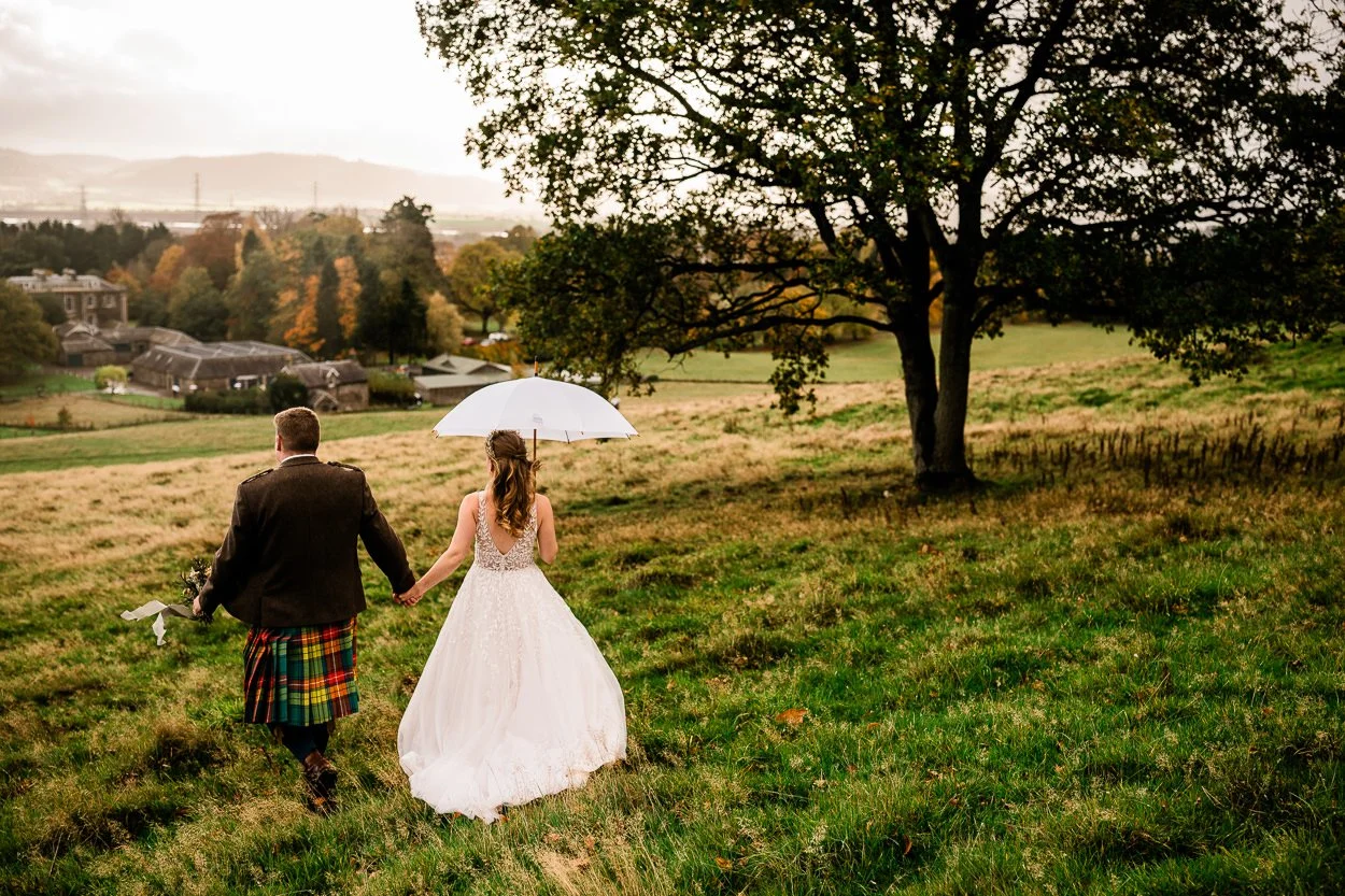 Bride and groom walking down hill towards Byre at Inchyra