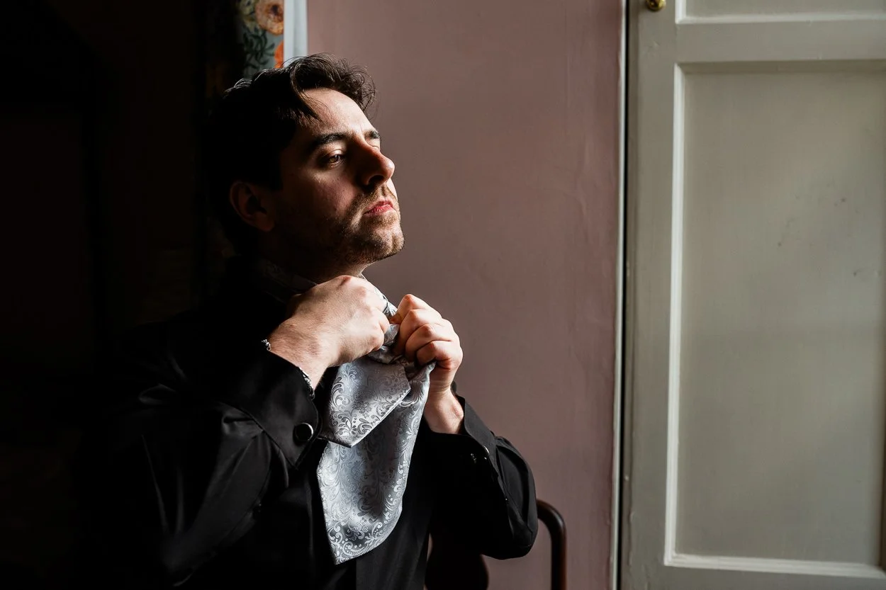 Groom doing up tie at Dalhousie Castle