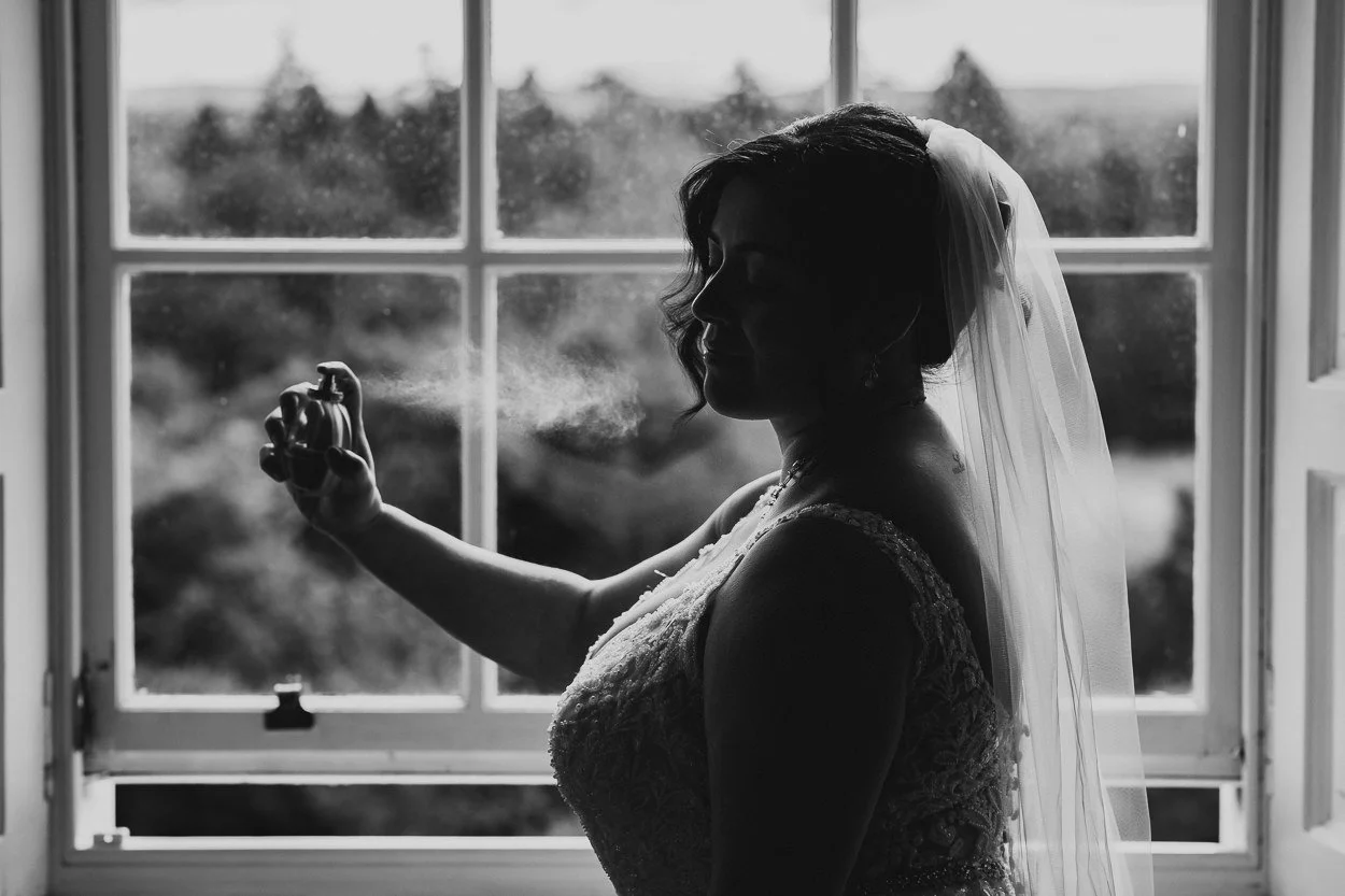 Black and white image of bride putting on perfume