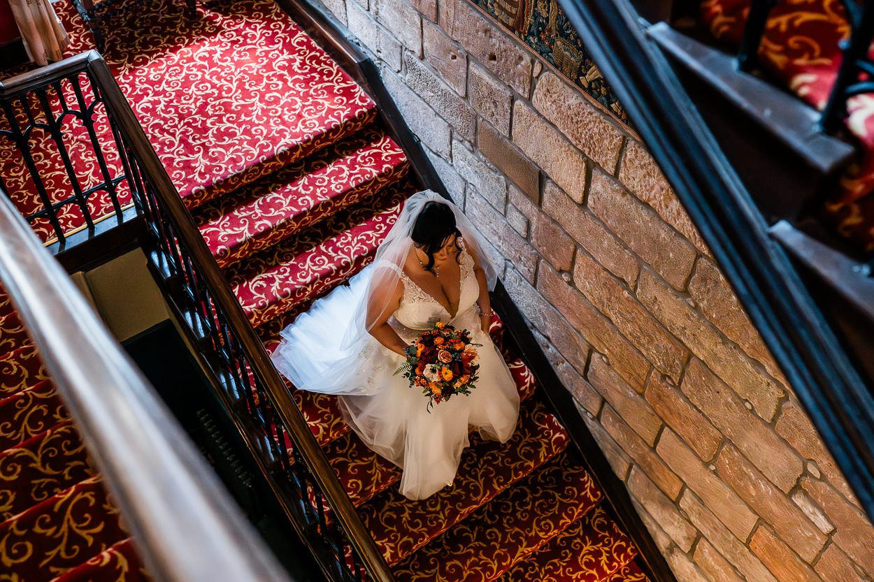Bride walking down Dalhousie Castle stairs to wedding ceremony