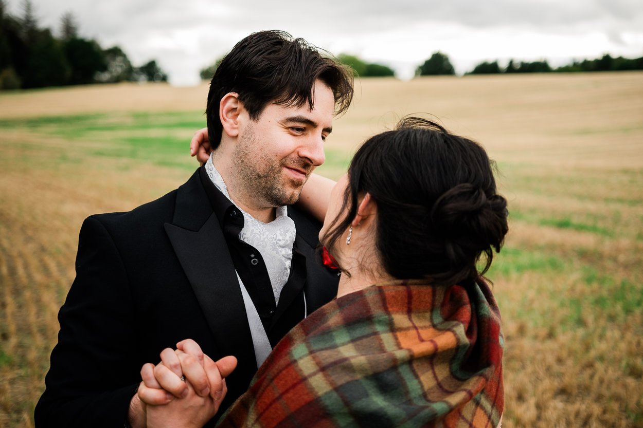 Bride and groom embracing in a field