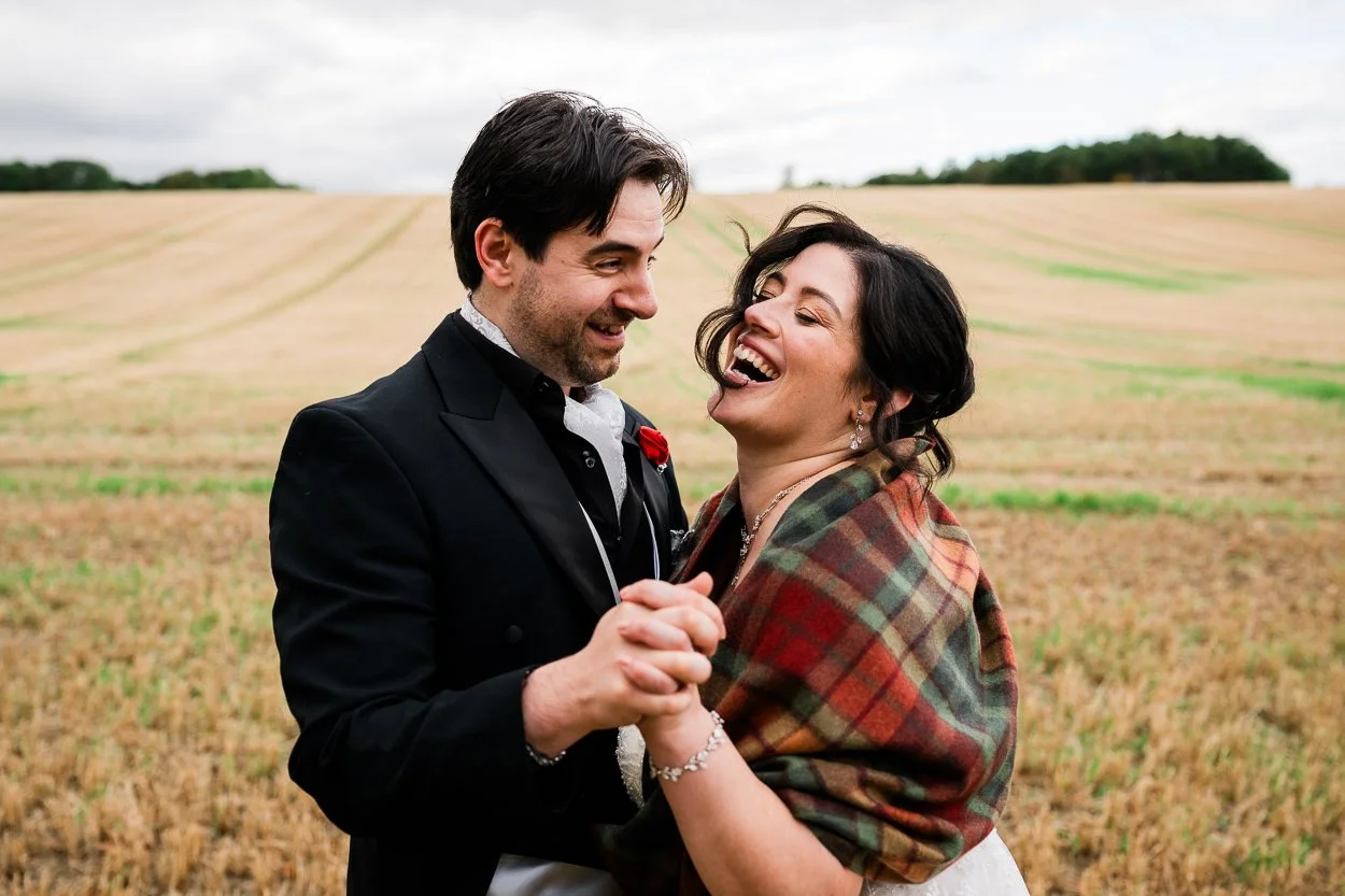 Big laughter from bride and groom in a field