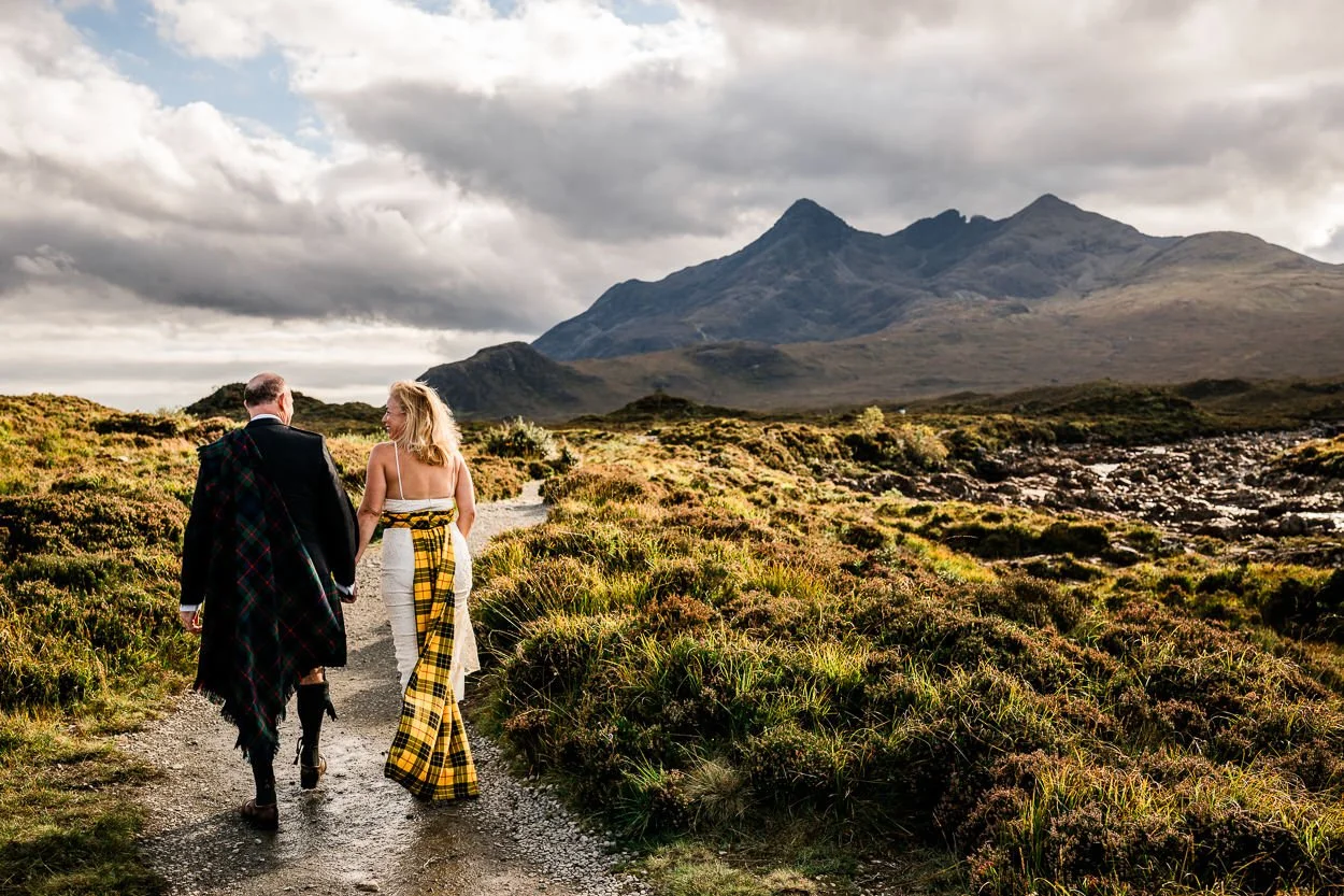 Bride and groom walking towards Cullin mountains Skye at elopement