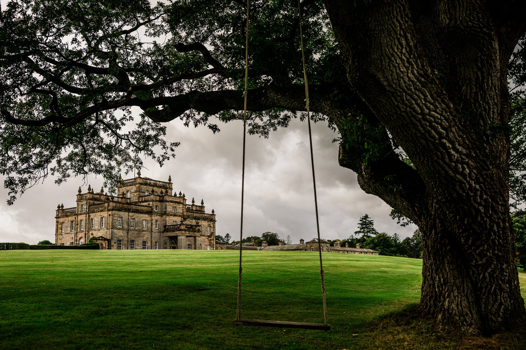 Kinmount House seen across the lawns beneath the branches of a large tree.