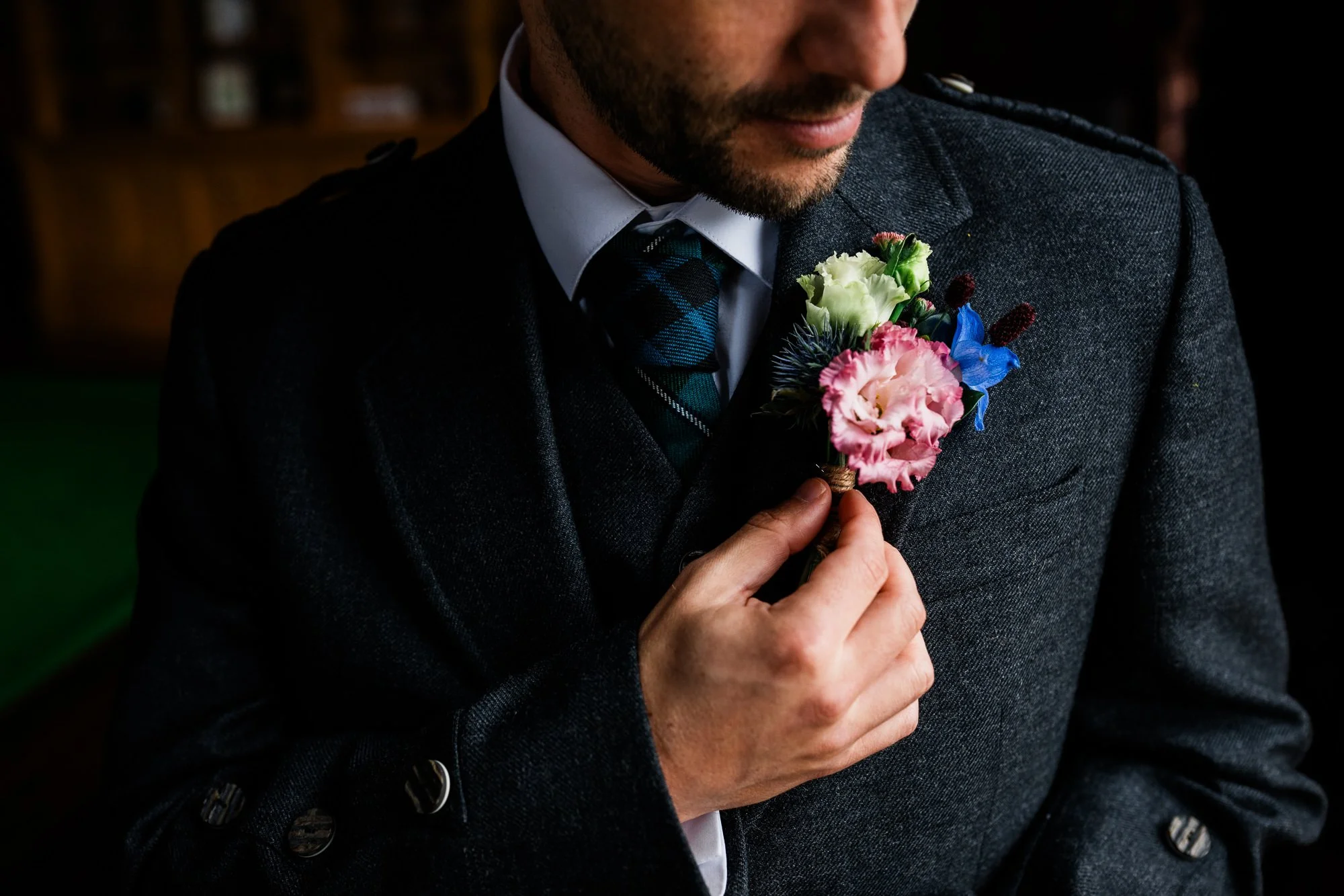 Close-up of Matthew’s floral buttonhole against his dark wedding jacket.