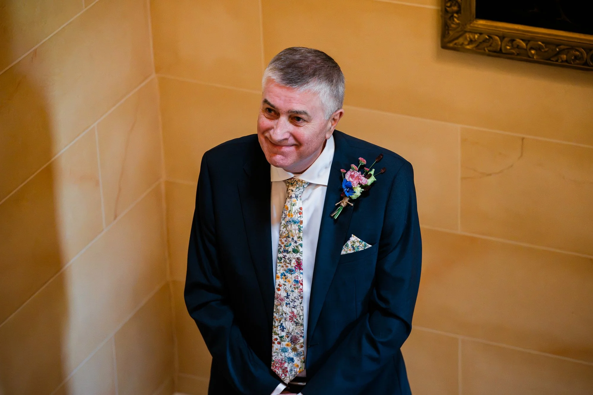 A wedding guest in a blue suit smiles before the ceremony.