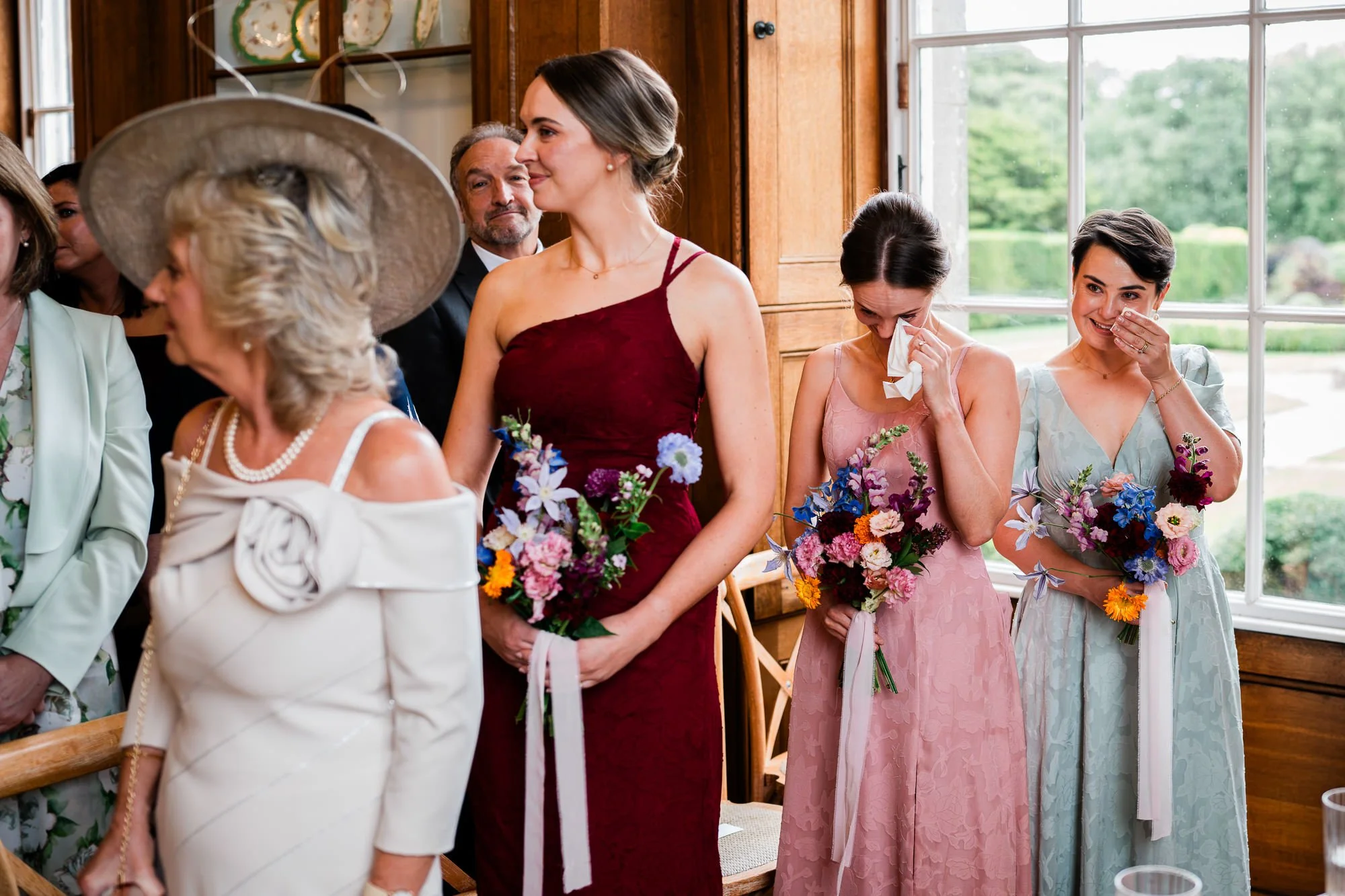 Bridesmaids in colourful dresses gather with a wedding guest before the ceremony.