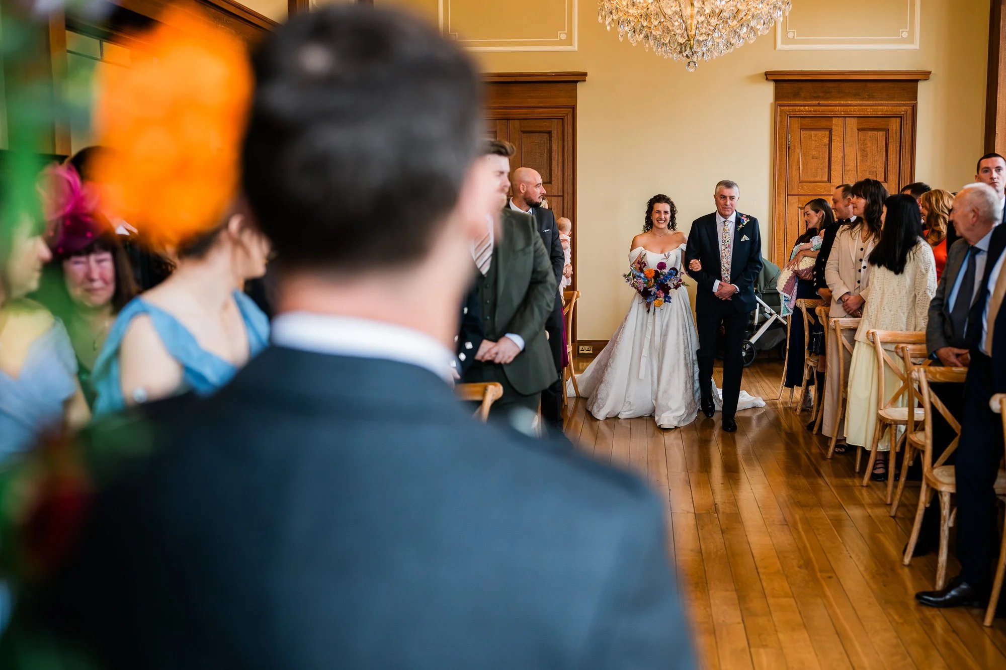 Matthew watches Aimee approach during their indoor wedding ceremony.