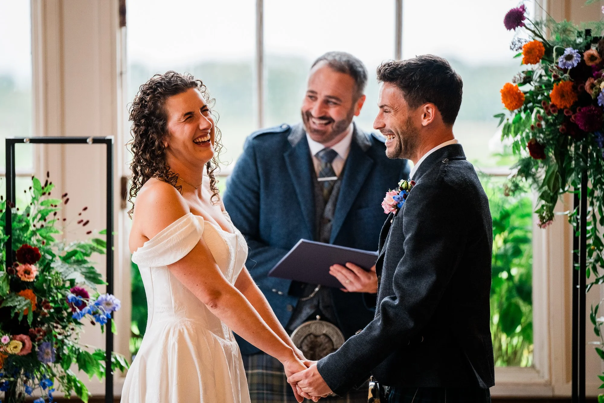 Aimee and Matthew exchange vows with their celebrant beside the window.