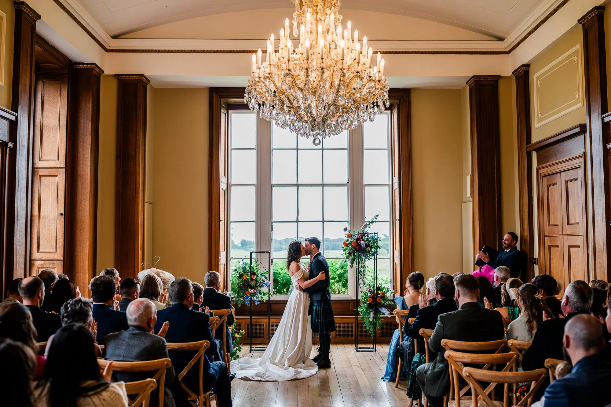 A wide view of the wedding ceremony beneath a chandelier at Kinmount House.