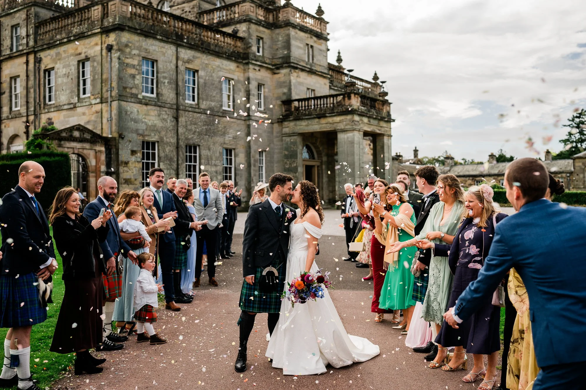 Guests throw confetti as Aimee and Matthew kiss outside Kinmount House.