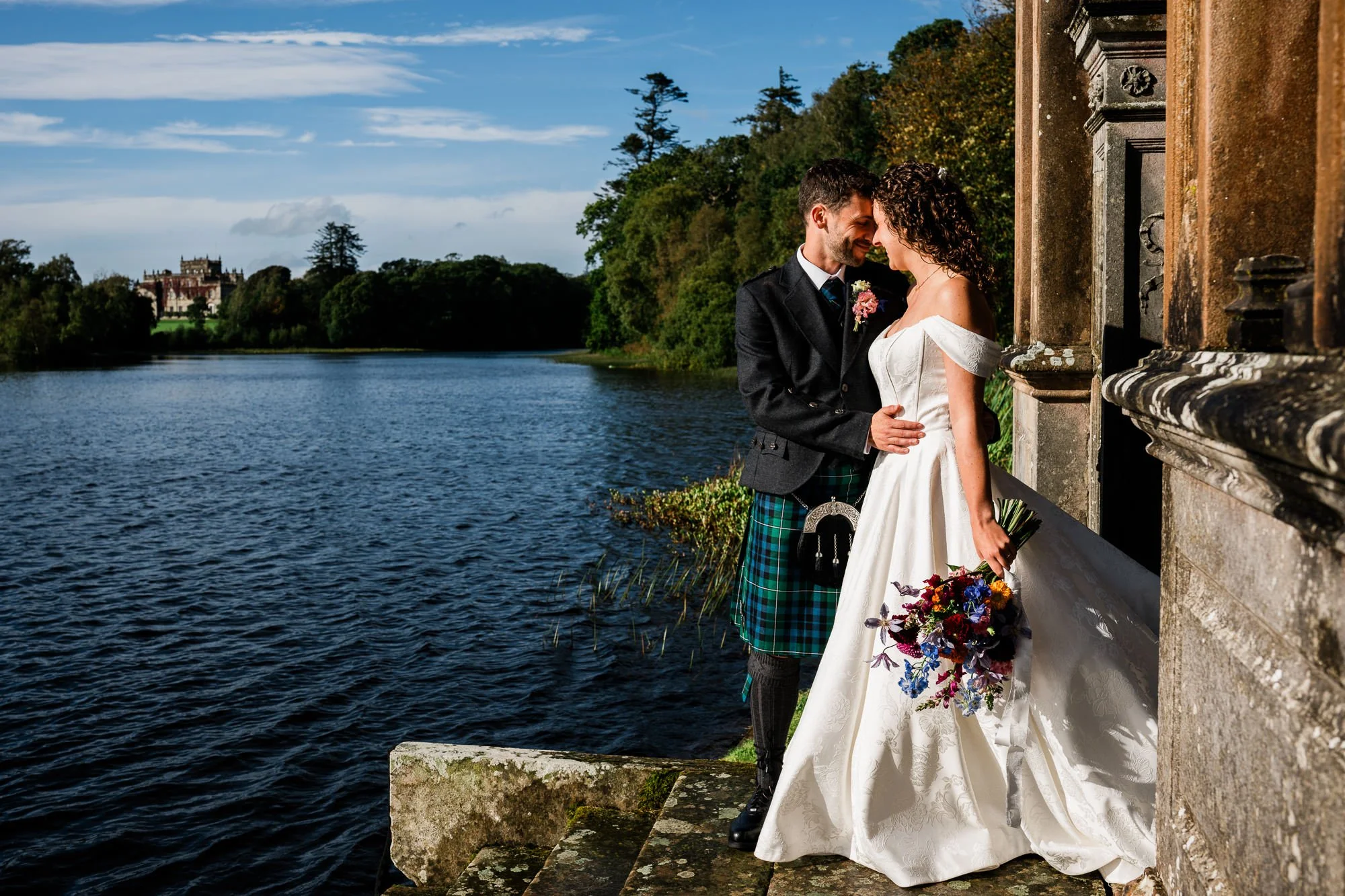 Aimee and Matthew share a kiss beside the water at Kinmount House.