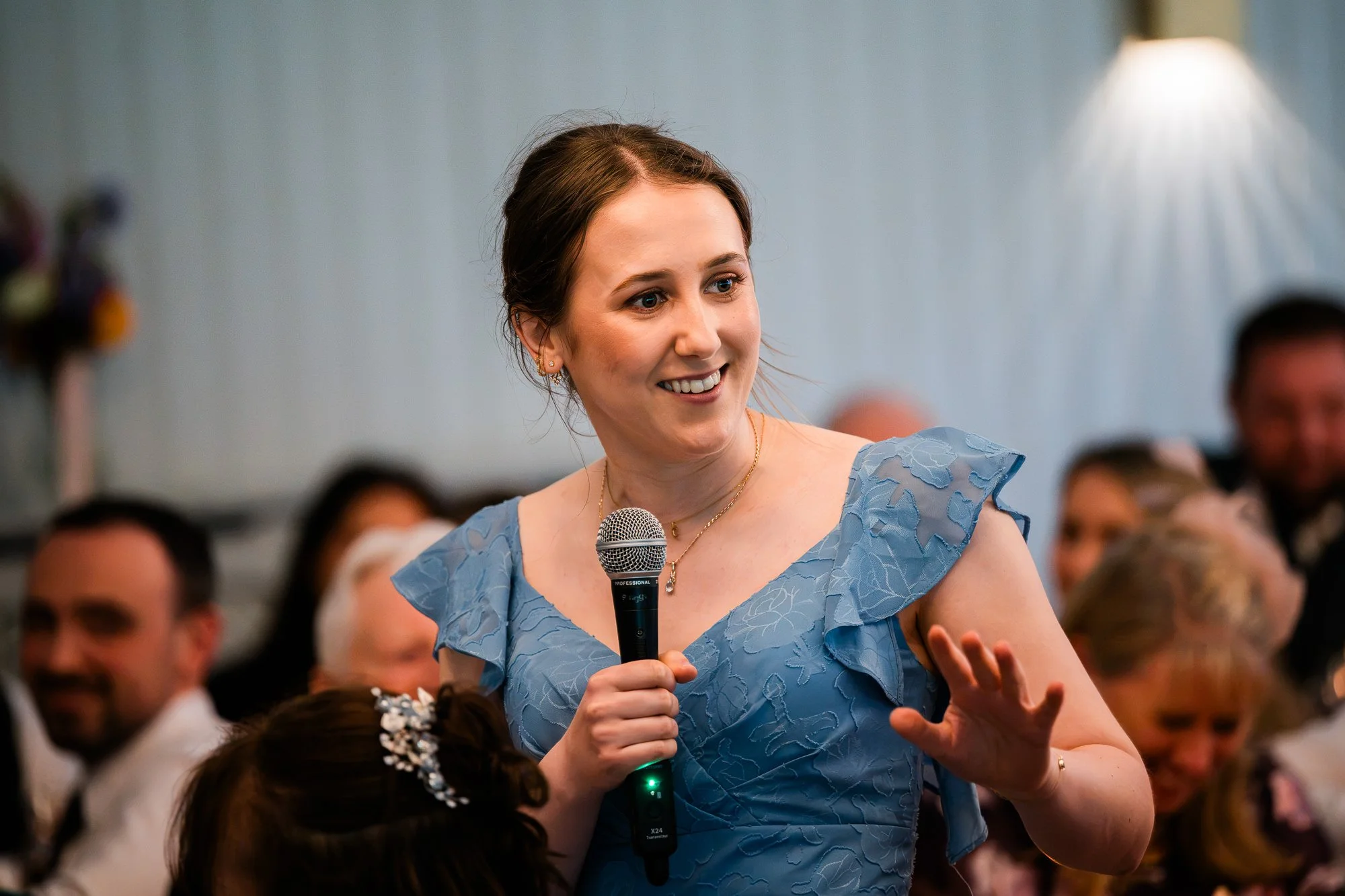 A wedding guest in a blue dress laughs during the speeches.