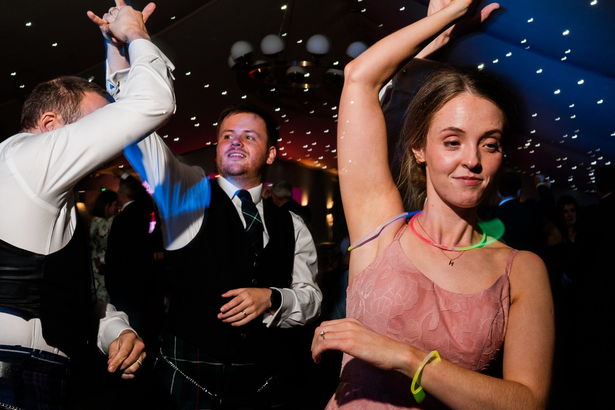 Wedding guests raise their arms on the dance floor at the evening reception.