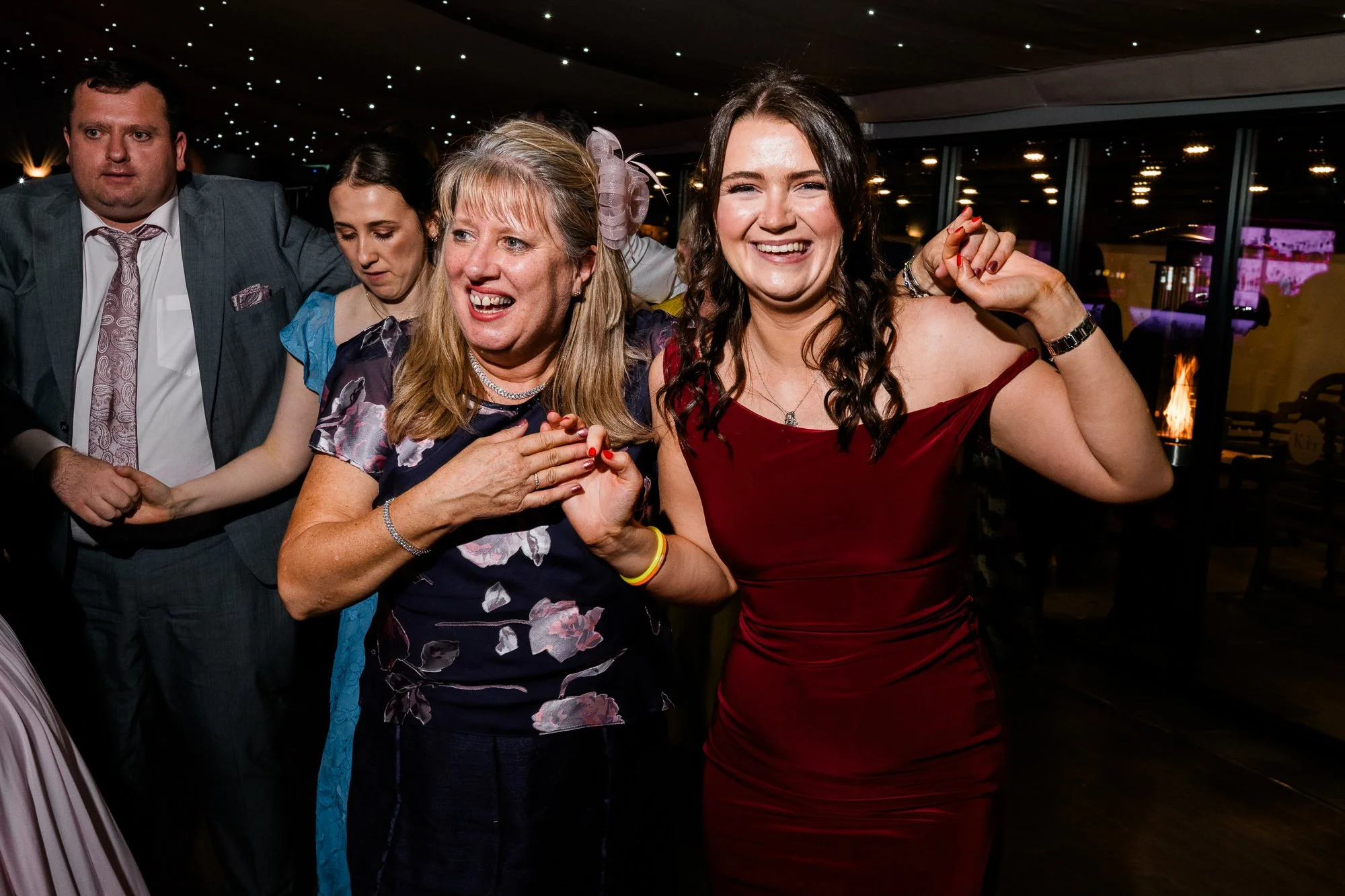 Friends dance together beneath colourful lights at Aimee and Matthew’s wedding.