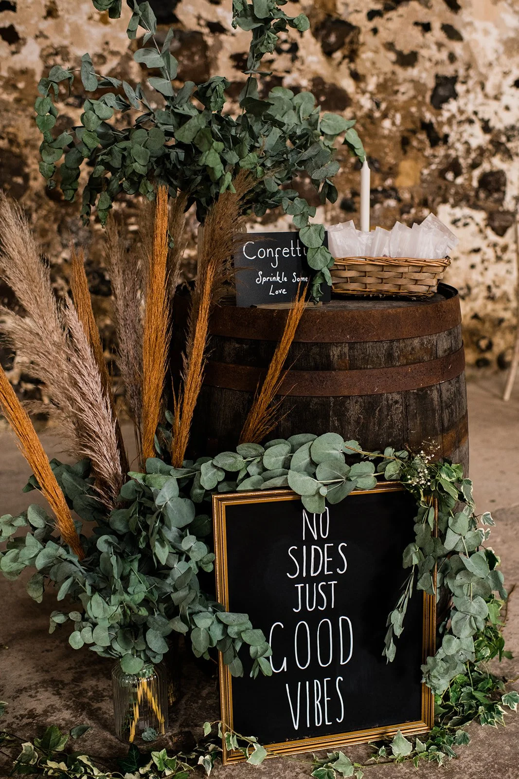 A chalkboard sign decorated with greenery welcomes guests to a rustic wedding at Pratis Barns.