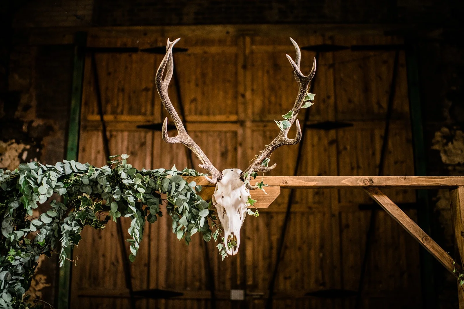 A stag skull and antlers above the greenery-covered ceremony backdrop at Pratis Barns.