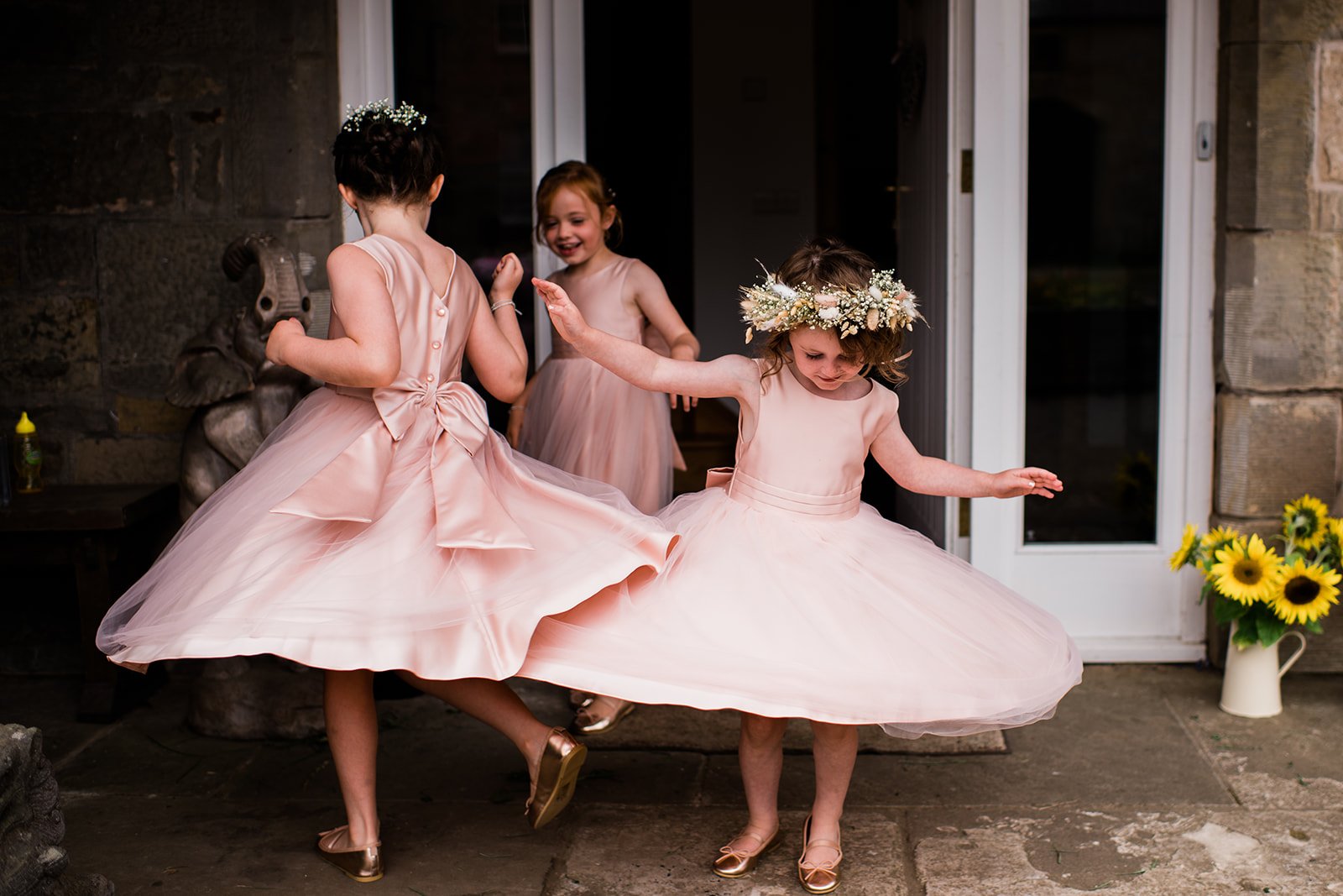 Young flower girls twirl in their pink dresses before the wedding.