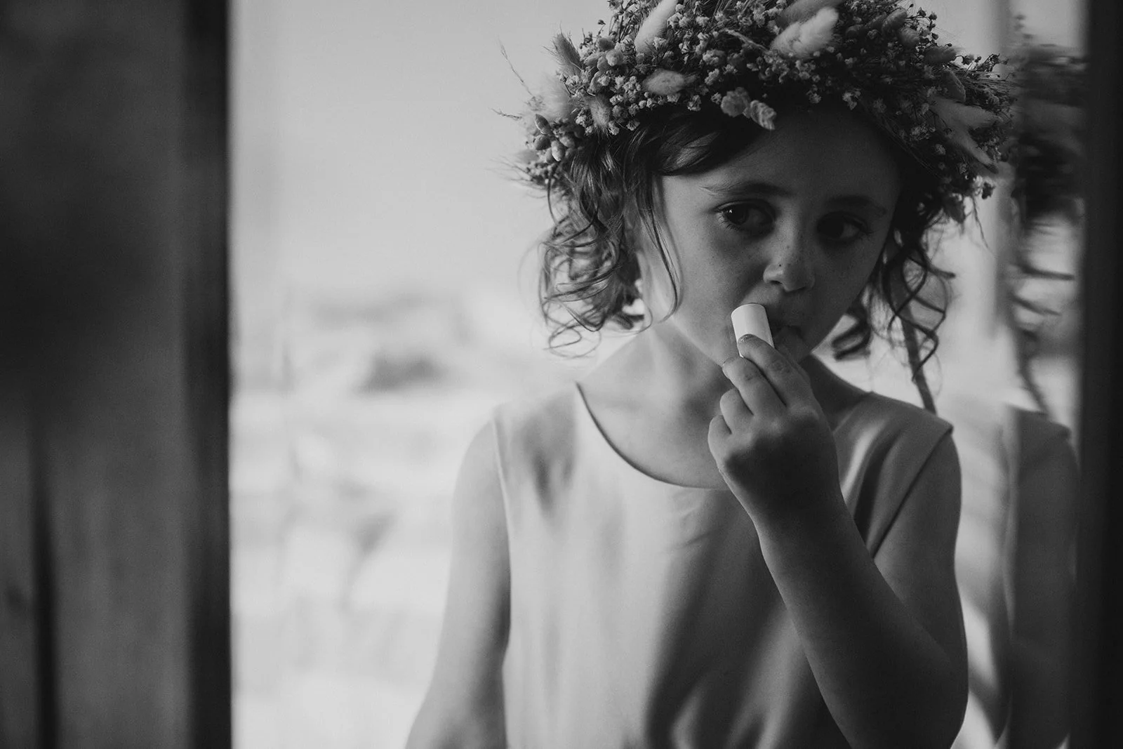 Black-and-white photograph of the bride getting ready beside a window.