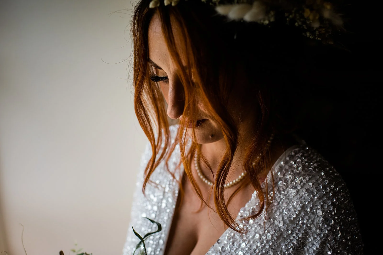 A close-up of the bride looking down, with her beaded wedding dress catching the light.