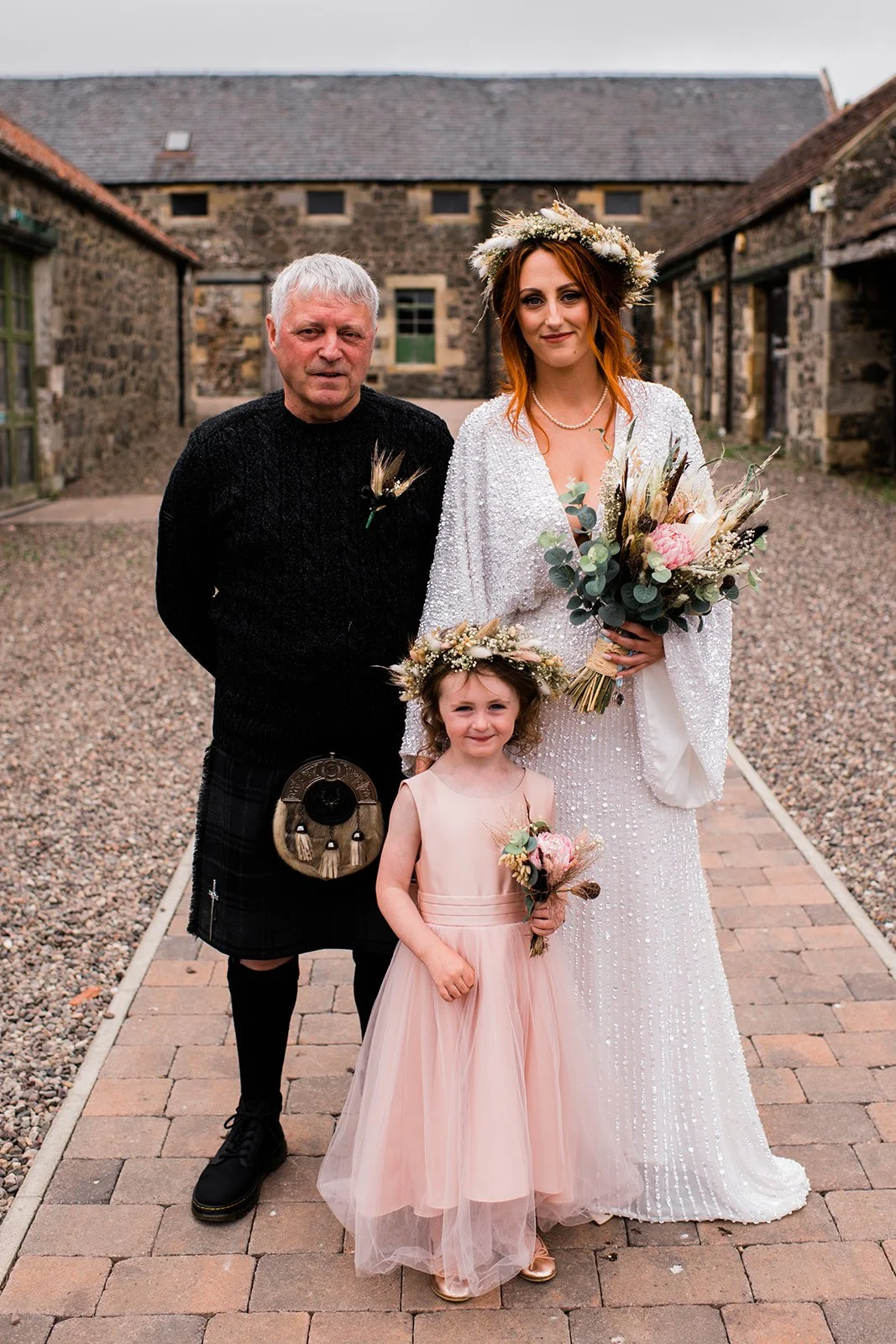 The bride walks arm in arm with her escort through the courtyard towards the ceremony.