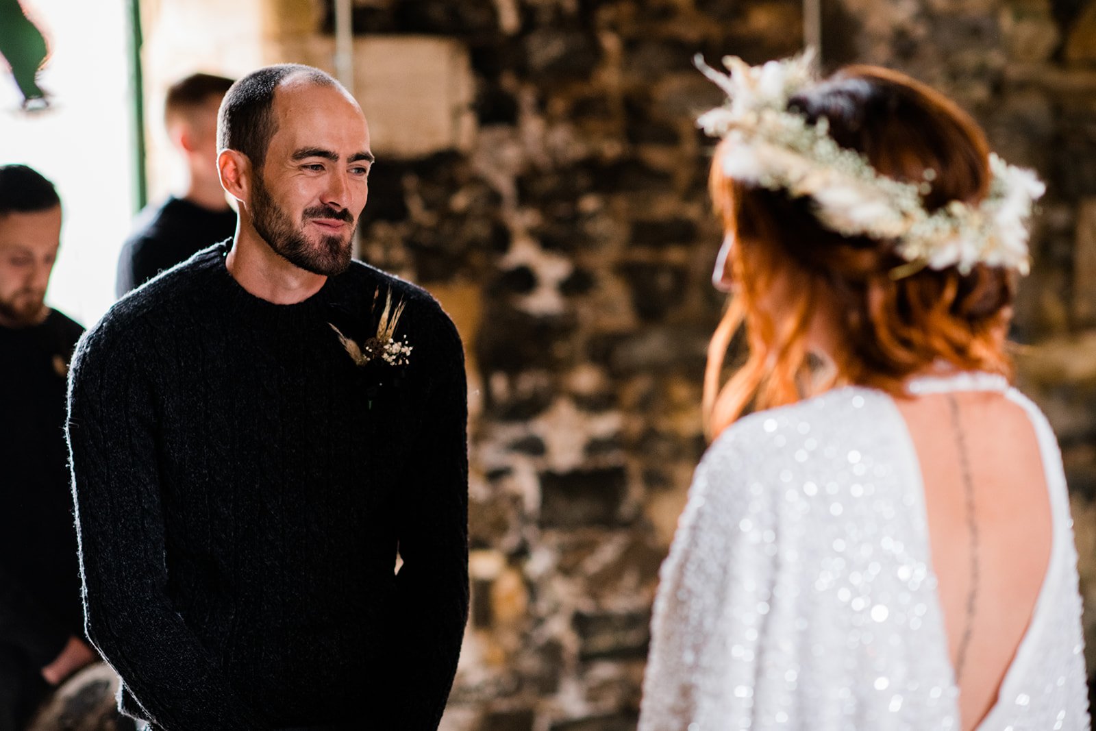 Bride and groom face each other during their wedding ceremony in the stone barn.