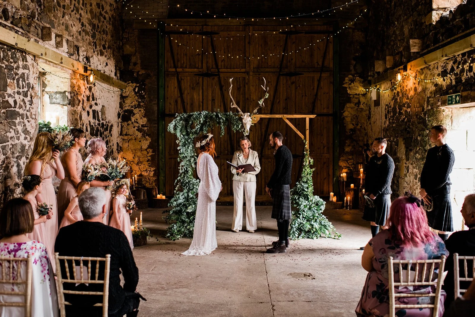 A wide view of the ceremony inside Pratis Barns, with guests seated beneath timber beams.