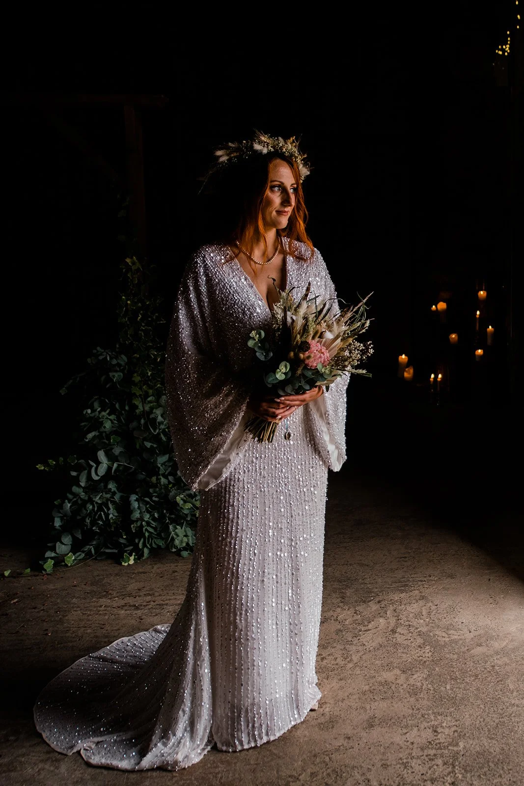 Full-length bridal portrait in the barn doorway, showing the beaded dress and bouquet.