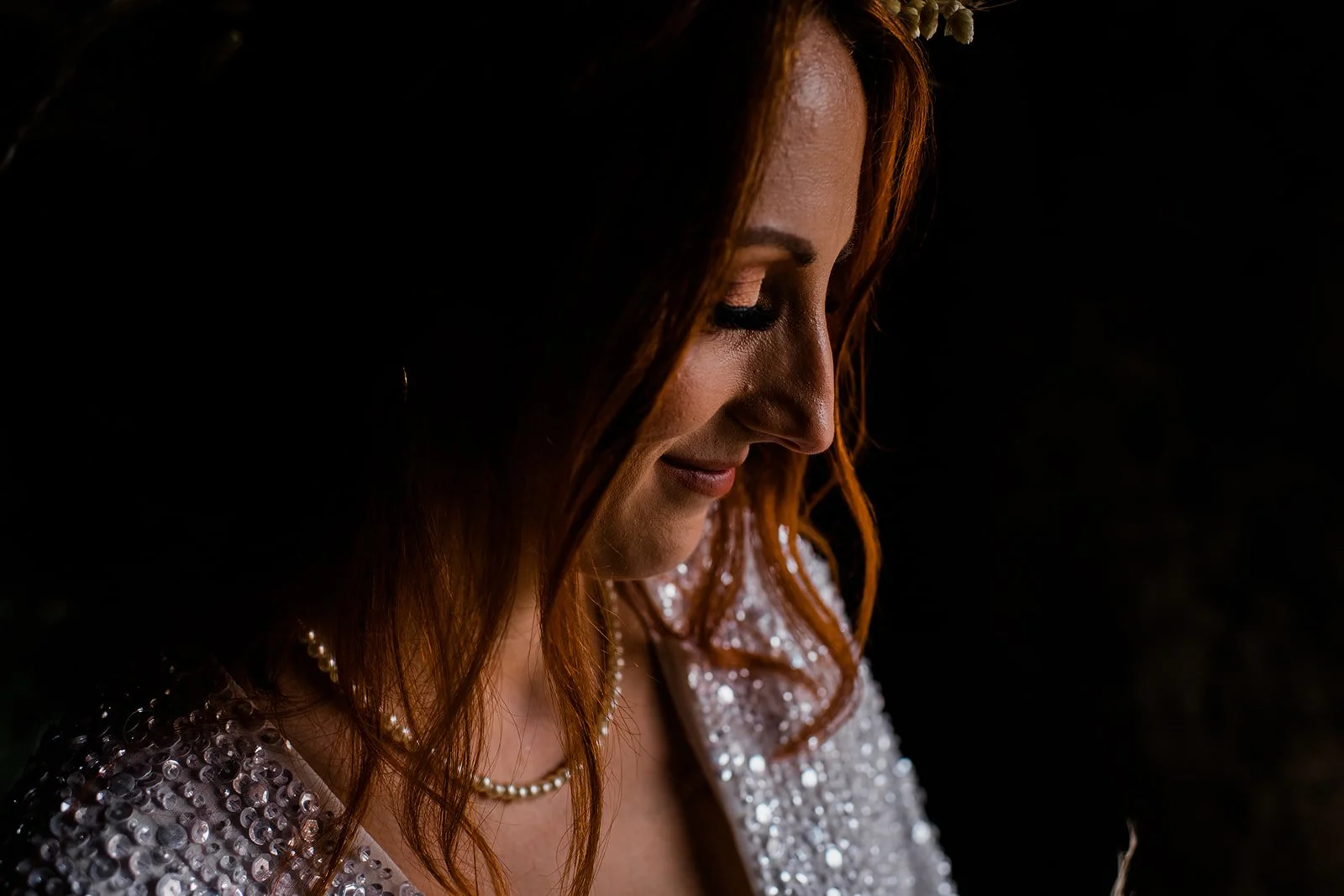 Close-up of the bride in soft window light, wearing a beaded wedding dress at Pratis Barns.