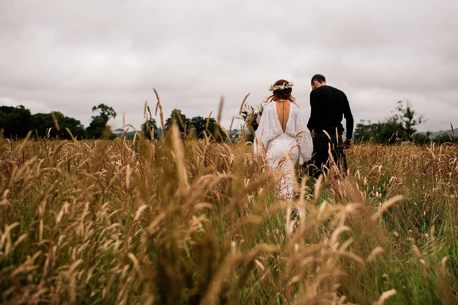A wide view of the bride and groom among long grasses in the Fife countryside.