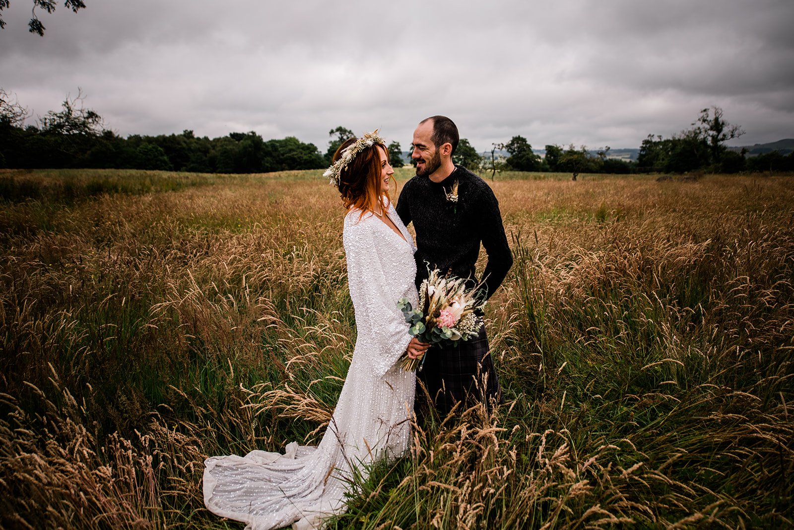 Bride and groom smile at each other in the long grass at Pratis Barns in Fife.