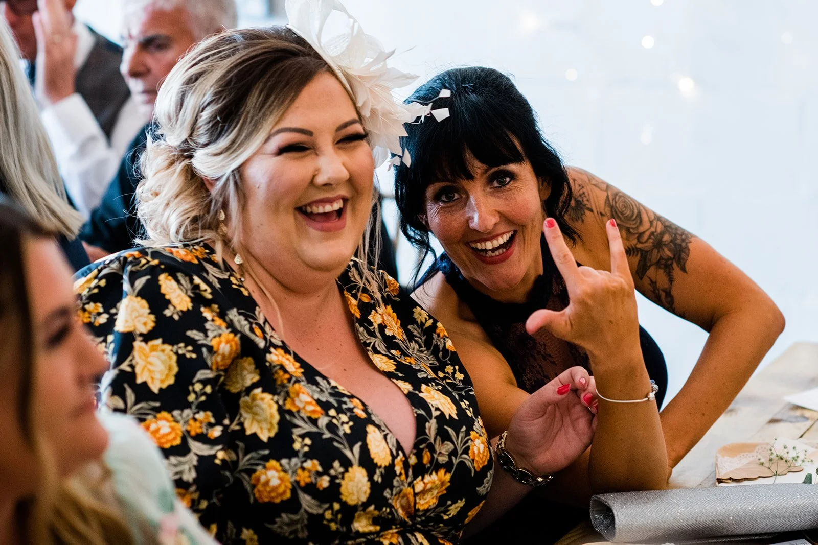 Two wedding guests laugh together at the reception table.