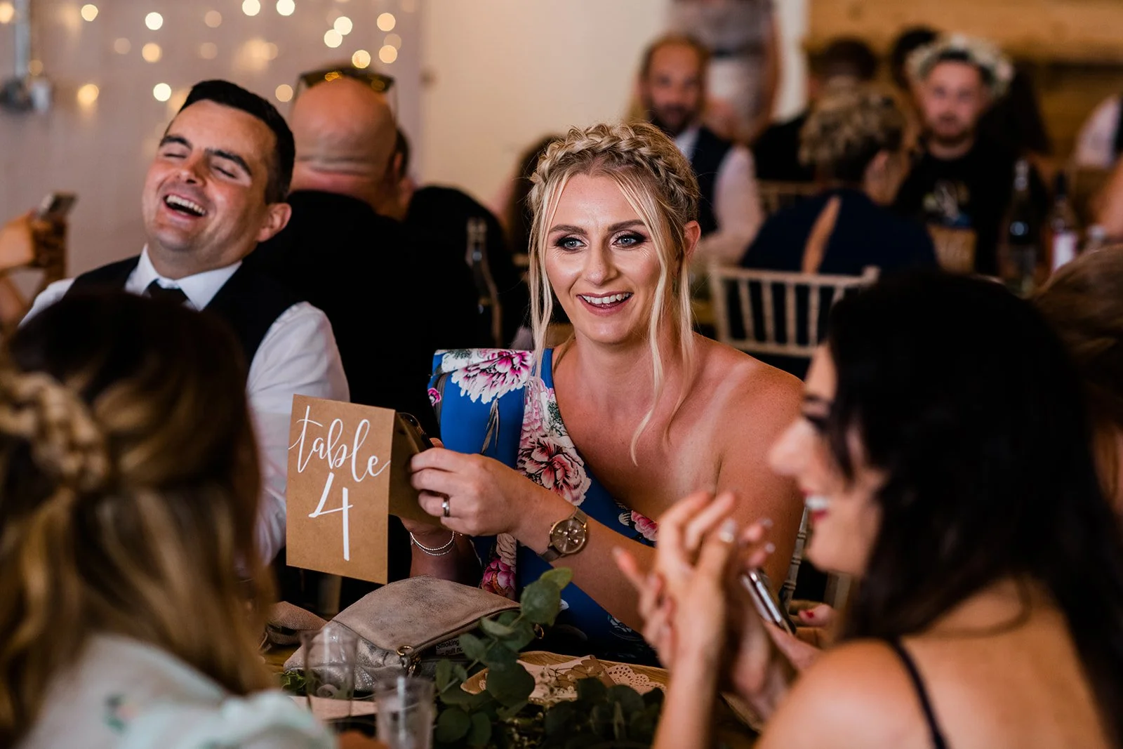 Wedding guests laugh and hold drinks during the reception speeches.