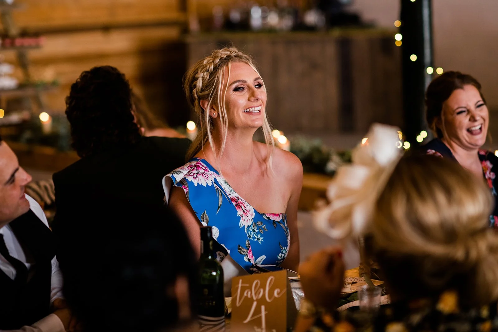 A guest in a blue dress reacts with surprise during the wedding speeches.